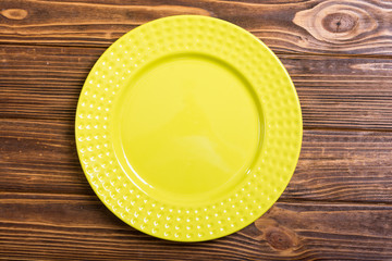 Empty yellow plate on wooden table