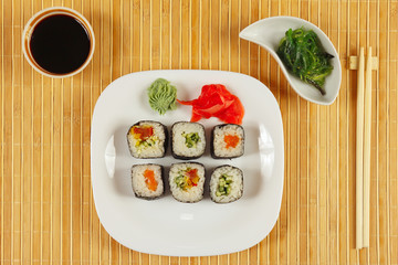 Sushi set, hiyashi wakame salad and soy sauce on a bamboo mat. View from above.