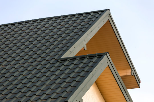 Close-up Detail Of New Modern House Top With Shingled Green Roof On Clear Blue Sky Background. Professionally Done Building And Construction Work, Real Estate Property, Contract Concept.