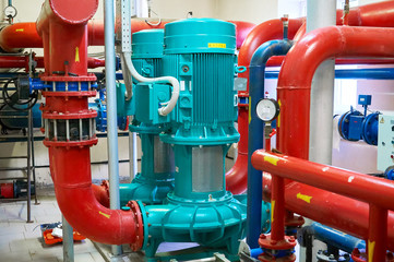 Two vertical engines painted blue with pumps connected to pipes painted red.