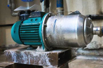 Old blue engine with a pump standing on a metal stand.