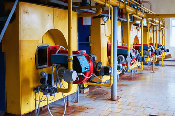 Boiler room with four large yellow cauldrons and red-blue burners.