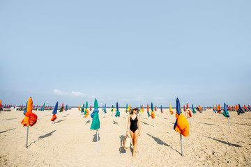 Woman walking on the beach with colorful umbrellas in Deauville, famous french resort in Normandy