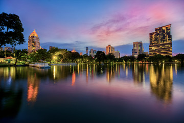 Fototapeta premium Lake view of Lumpini Park in the Thai capital's city centre with buildings in Bangkok