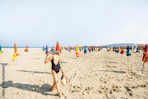 Woman Walking On The Beach With Colorful Umbrellas In