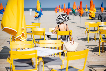 Woman sitting on the yellow chairs on the beach with colorful umbrellas in Deauville, France