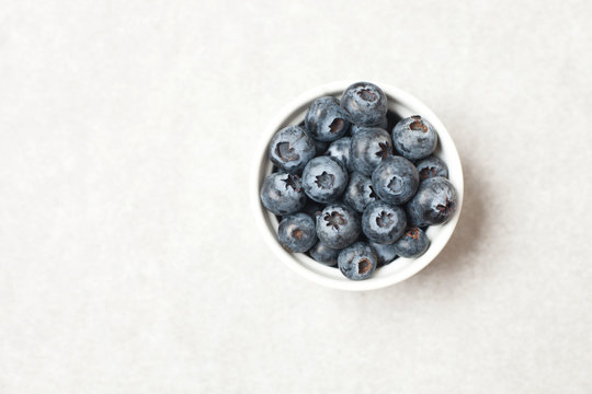 Overhead image of a bowl with blueberries on a white background
