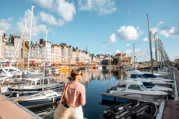 Young woman tourist enjoying beautiful view on the harbour traveling in Honfleur town in Normandy,...