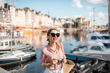 Young woman tourist enjoying beautiful view on the harbour traveling in Honfleur town in Normandy, France