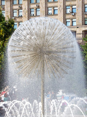 A fountain in the form of a ball with built-in tubes, from which water flows on the city square_