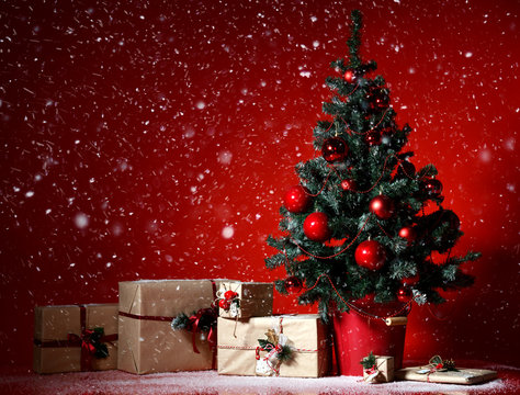 Christmas tree decorated with red patchwork ornament balls and craft presents gifts for new year 2019  under heavy snow 