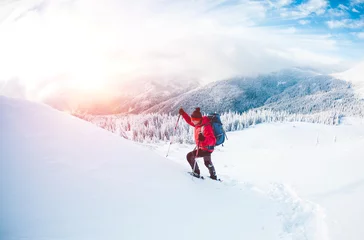 Gordijnen A man in snowshoes in the mountains. © zhukovvvlad