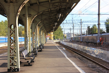 Old City Train Station Empty Outdoor Platform with Vintage Seats and No Passengers Around on Summer Day. Vintage Architecture of Railway Station in St. Petersburg, Russia  