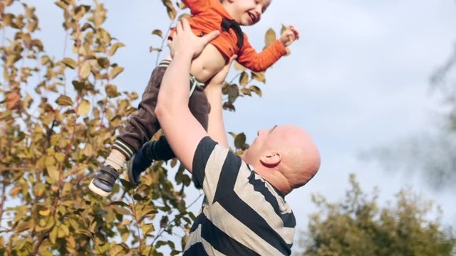 Concept happy family. Father throwing his adorable son in the air.