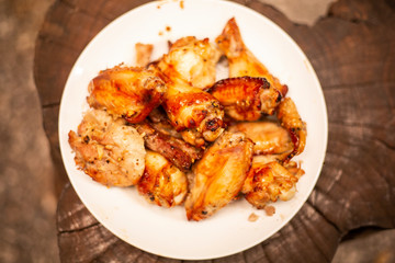 Spicy chicken wings and legs grilling with hot flames.