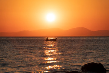 Obraz premium Sonnenuntergang am Meer, Fischerboot fährt der Küste entlang