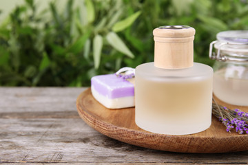 Natural herbal oil and lavender flowers on table against blurred background. Space for text