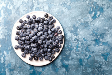 Fresh blueberries on a white plate and blue background. Concept  Healthy Food. Diet Nutrition .Copy space for Text. Top View. Flat Lay.selective focus.