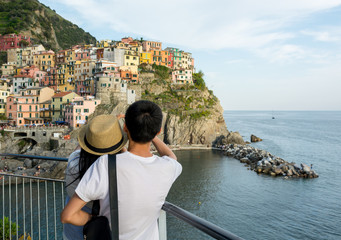 Tourist couple looking at traditional port town embraced in a hug.