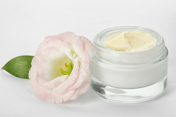 Jar with cream and flower on white background. Hand care cosmetics