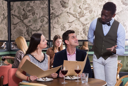 African American waiter recommending dishes from restaurant menu