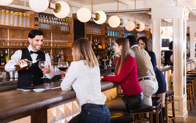 Portrait of barman and people who are standing near bar counter in luxurious restaurant
