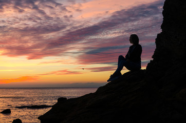 Fototapeta premium The silhouette of girl that standing on the stone near the sea