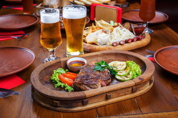 Hot steak with sauce and vegetables. On a wooden table