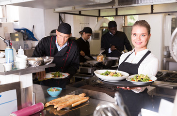 Waitress with dishes in kitchen