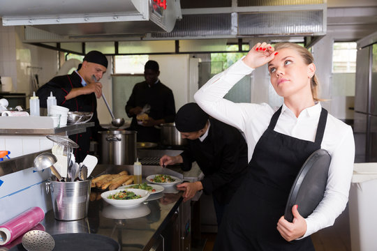 Unhappy waitress waiting dishes in kitchen
