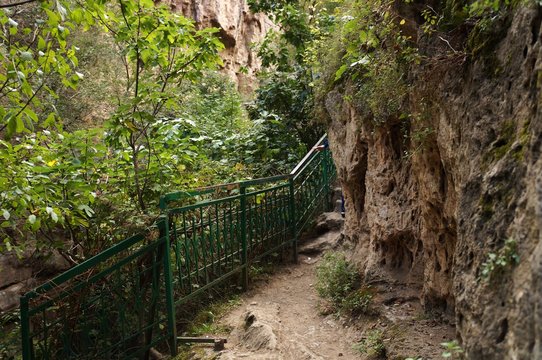 Железное ограждение в зелёном каньоне из коричневых скал!