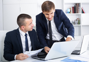 cheerful two males coworkers working in firm office