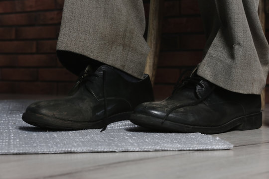 Poor man wearing old dirty shoes indoors, closeup