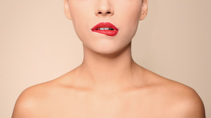 Beautiful young woman with red lips on color background, closeup