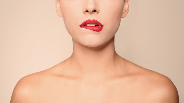 Beautiful young woman with red lips on color background, closeup