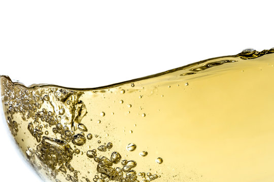 Fototapeta Splash white wine in glass with bubbles close-up macro texture isolated on top on white background. Wave of white wine with beautiful fizz.