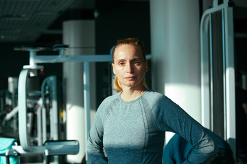 Fitness woman gym fifty plus menopause blonde exercise equipment dumbbells orbitrek windows sunset...