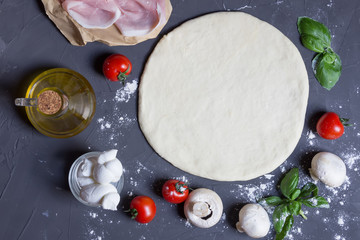 Dough basis with and ingredients for pizza mushrooms, tomatoes, ham, mozzarella, oil, basil on the...