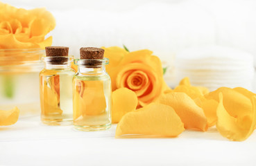 Essential oils bottles with fresh yellow roses, close soft light. Botanical treatment aromatherapy
