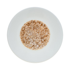 Top view of a single multigrain rice cake on a plate isolated on a white background.