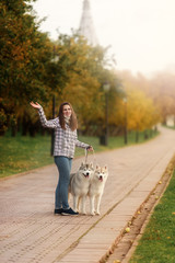 Naklejka na ściany i meble girl plays with her dog in fallen autumn leaves