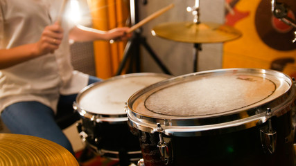 Plakat Repetition. Ginger girl plays on drums in the studio. Focus on drums