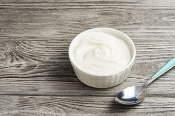 bowl of sour cream yogurt on gray wooden background.
