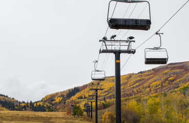 autumn landscape-empty ski resort chairlift climbing up a mountain covered in bright autumn colors
