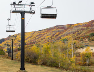 autumn landscape-empty ski resort chairlift climbing up a mountain covered in bright autumn colors