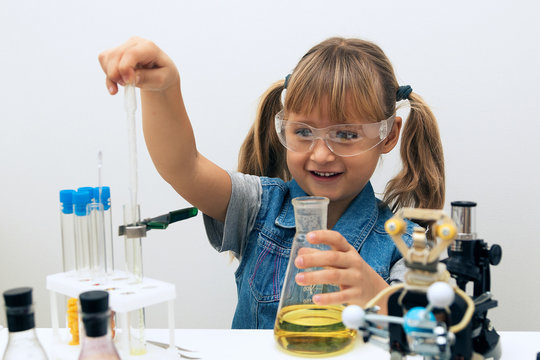 Science school, Workshop. A girl child collect molecules and conduct chemical experiments. On the table is a robot. STEM education. Science and technology.