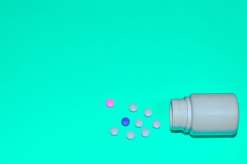 Assorted pharmaceutical medicine pills, tablets and capsules and bottle on blue background. Space for text.