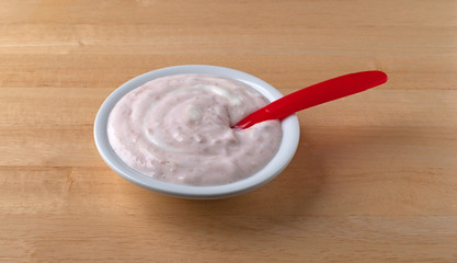 Bowl of strawberry rhubarb yogurt on a wood table