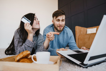 Couple choosing goods at online store using laptop and credit card. E-shopping, order, retail, business concept