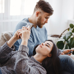 Couple using smart phones on a couch. Young people chatting online. Internet and gadget addiction